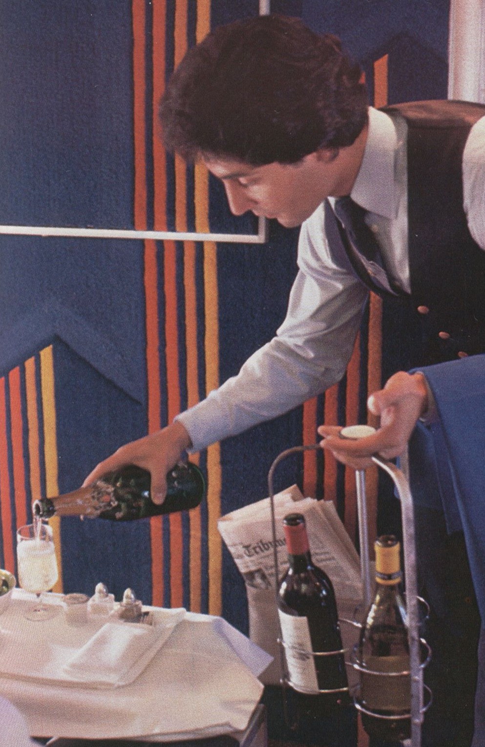 1980 A Pan Am flight attendant carries both red and white wine as well as champagne to offer each First Class customer their choice.